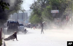 A security force and a civilian lie low at the site of a suicide attack after the second bombing in Kabul, Afghanistan, April 30, 2018. A coordinated double suicide bombing hit central Kabul on Monday morning.