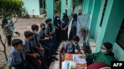 Seorang petugas kesehatan tampak bersiap melakukan tes antigen COVID-19 kepada sejumlah siswa di salah satu SMP di Surabaya, pada 9 Juni 2022. (Foto: AFP/Juni Kriswanto)