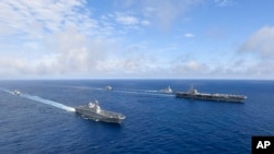 Kapal induk bertenaga nuklir AS USS Ronald Reagan, kanan, dan kapal helikopter platform pendaratan (LPH) Korea Selatan (LPH) Marado, kedua dari kiri, berlayar selama latihan militer bersama di lokasi yang dirahasiakan, Sabtu, 4 Juni 2022. (Foto: via AP)