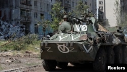 A service member of pro-Russian troops rides on top of an armored personnel carrier amid Russia's invasion of Ukraine, in the town of Popasna in Ukraine's Luhansk region, June 2, 2022. 