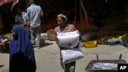 FILE - A man carries a sack of wheat flour imported from Turkey in the Hamar-Weyne market in Mogadishu, Somalia, May 26, 2022. Families across Africa are paying about 45% more for wheat flour as Russia's war in Ukraine blocks exports from the Black Sea.