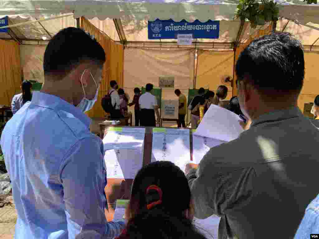 ពលរដ្ឋពិនិត្យមើលបញ្ជីឈ្មោះអ្នកបោះឆ្នោត នៅសង្កាត់ចាក់អង្រែលេី ខណ្ឌមានជ័យ នៅក្នុងបោះឆ្នោតជ្រេីសរេីសក្រុមប្រឹក្សាឃុំសង្កាត់អាណត្តិទី៥​ នៅថ្ងៃទី៥​ ខែមិថុនា​ ឆ្នាំ២០២២។ (កាន់​ វិច្ឆិកា/វីអូអេ) 