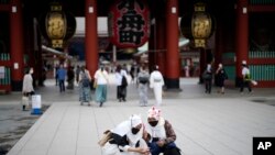 Turis asing mengenakan masker tengah berfoto selfie di distrik Asakusa di Tokyo, Jumat, 10 Juni 2022. (Foto: AP/Eugene Hoshiko)