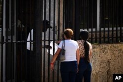 People wait their turns outside the U.S. embassy the day after it reopened its consular services in Havana, Cuba, Wednesday, May 4, 2022. (AP Photo/Ramon Espinosa)
