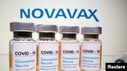 FILE - Vials with a sticker reading, "COVID-19 / Coronavirus vaccine / Injection only" and a medical syringe are seen in front of a Novavax logo on Oct. 31, 2020. 
