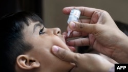 Seorang anak yang tinggal di wilayah miskin di Karachi, Pakistan, mendapatkan vaksin polio dalam program vaksinasi polio dari rumah ke rumah yang dilakukan di negara tersebut pada 23 Mei 2022. (Foto: AFP/Asif Hassan)