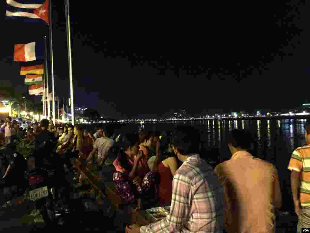 អ្នក​ទស្សនា​អង្គុយ​នៅ​តាម​ដង​ទន្លេ​ចតុមុខ​មើល​ទៅ​ទន្លេ​ដែល​ពំុ​មាន​ប្រទីប​និង​ទូកង​ទេ។ ទិដ្ឋភាព​នៅ​មុខ​ព្របរមរាជវាំង​នៅ​ថ្ងៃ​​ចុង​ក្រោយ​នៃ​ពិធី​បុណ្យអំុទូក​ កាល​ពី​ថ្ងៃ​ទី​២៦ ខែ​វិច្ឆិកា ឆ្នាំ​២០១៥។ (ផន បុប្ផា/VOA)