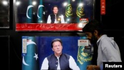 A shopkeeper tunes a television screen to watch the speech of Pakistani Prime Minister Imran Khan, at his shop in Islamabad, Pakistan, March 31, 2022. 
