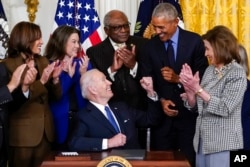 Presiden Joe Biden (tengah) melihat ke arah mantan Presiden Barack Obama usai menandatangani Keppres mengenai "Affordable Care Act" di Gedung Putih, Selasa (5/4).