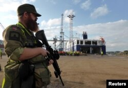 FILE - A Norwegian soldier stands guard as German military equipment is unloaded at Fredrikstad, Norway, Sept. 7, 2018.