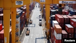 FILE - A truck driver stands next to his truck as he gets ready to transport a shipping container at Pusan Newport Terminal in Busan, South Korea, July 1, 2021. 