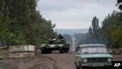 Ukrainian servicemen ride atop of a tank on a road in the recaptured area of Izium, Ukraine, Sept. 14, 2022. 