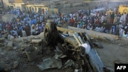 Des badauds autour des restes d'un avion de ligne nigérian tombé dans un quartier résidentiel bondé de Kano, le 5 mai 2002.