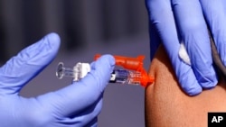 FILE - A patient is given a flu vaccine at a community clinic in Lynwood, Calif., Oct. 28, 2022. A rapidly intensifying flu season is straining some U.S. hospitals already overburdened with patients sick from other respiratory infections.