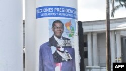 A campaign poster for Equatorial Guinea President Teodoro Obiang Nguema is pasted over a campaign poster of opponent Essono Ondo Andress, in Malabo, Nov. 17, 2022.