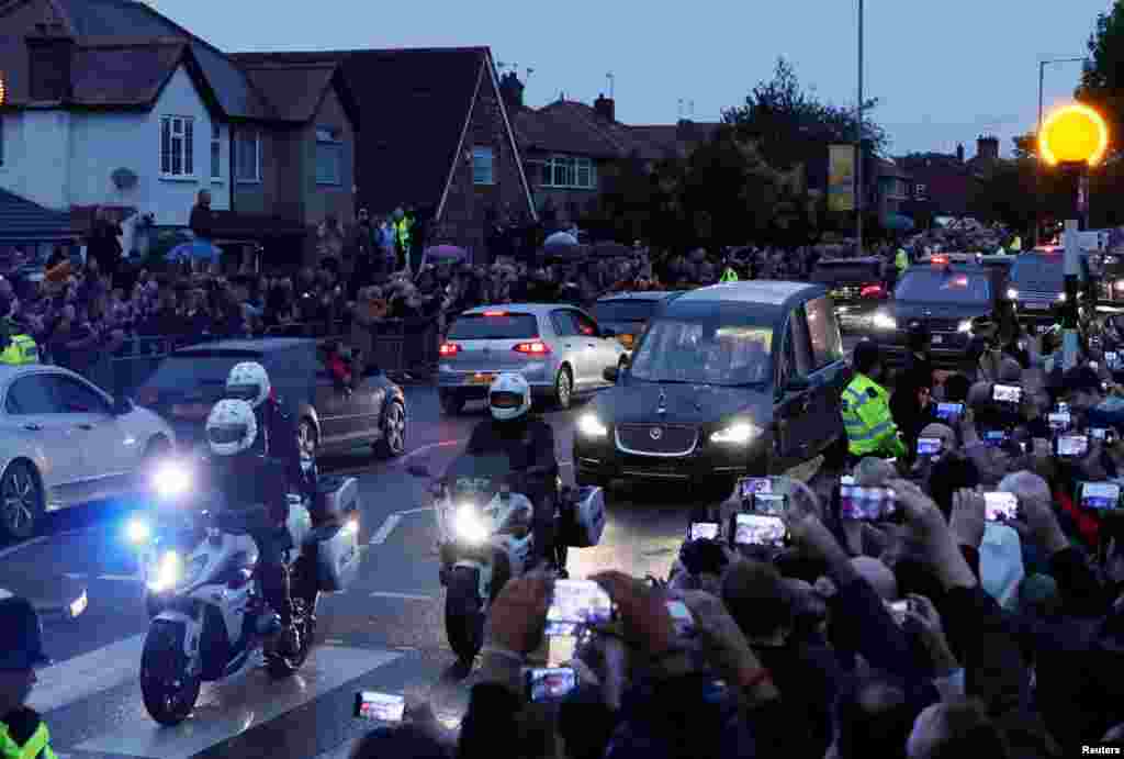 People watch the hearse carrying the coffin of Britain's Queen Elizabeth, following her death, after leaving RAF Northolt, in London, Sept. 13, 2022.