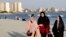 FILE - Women walk on the shore of the Persian Gulf Martyrs' Lake in Tehran, July 6, 2019. Some women in Iran have been taking off mandatory headscarves, or hijabs, in public, risking arrest.