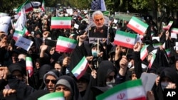Iranian pro-government demonstrators attend a rally to condemn recent anti-government protests as they hold Iranian flags and a poster of the late Revolutionary Guard Gen. Qassem Soleimani, who was killed in Iraq in a U.S. drone attack in 2020, in Tehran, Iran, Sept. 23, 2022.