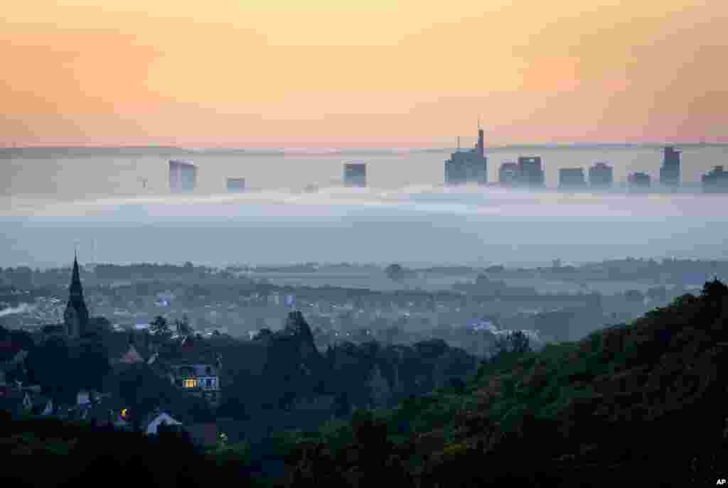 ផ្សែង​អព្ទ​ហ៊ុមព័ទ្ធ​ជុំវិញ​អគារ​នានា​នៅ​តំបន់​ពាណិជ្ជកម្ម​ក្នុង​ក្រុង Frankfurt ប្រទេស​អាល្លឺម៉ង់ ជាមួយ​នឹង​ក្រុង​ Kronberg នៅ​ខាង​ផ្នែក​មុខ​រូបថត។