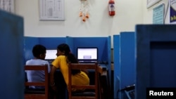 FILE - A mother and son talk as they work on laptop computers, in Punarbas, Kanchanpur district, southwestern Nepal, Aug. 8, 2022. Nepal’s government is now requiring from any medium or person wanting to post a video online to first purchase a license.