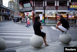 People rest on stone barricades on a street, following the coronavirus disease (COVID-19) outbreak, in Shanghai, China, September 9, 2022. (REUTERS/Aly Song)