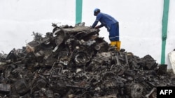 Un ouvrier se tient debout sur des tas de ferraille d'aluminium et de métaux automobiles à recycler à l'usine Romco de Lagos, le 26 août 2022.