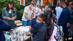 A woman, part of a group of immigrants who had just arrived, holds a child as they are fed outside St. Andrews Episcopal Church, Sept. 14, 2022, in Edgartown, Massachusetts, on Martha's Vineyard.
