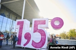 FILE - Demonstrators from Extinction Rebellion push a cart in the shape of the climate target "1.5" in Berlin, Germany on October 24, 2021. (Annette Riedl/dpa via AP, File)