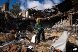 Tetyana, 68, collects wood to heat for heating from a destroyed school where Russian forces were based in the recently retaken area of Izium, Ukraine, Sept. 19, 2022.