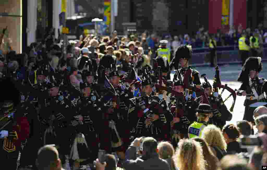 Bagpipers play as they march after the departure of the Queens cortege with the hearse carrying Queen Elizabeth's coffin from St. Giles' Cathedral in Edinburgh, Scotland, Sept. 13, 2022.