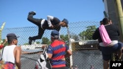 FILE - Salvadorean migrants climb and jump over a fence to get to the Guatemala-Mexico international border bridge in Ciudad Tecun Uman, Guatemala, Nov. 2, 2018. 