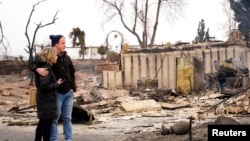 Christian Harrison and Deb Harrison react to the damage of their home in The Enclave after the wildfire in Louisville, Colo., Dec. 31, 2021.