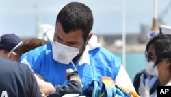 Un secouriste accueillant un bébé près de Ragusa, en Sicile