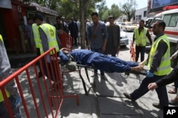 Afghan men carry a wounded man after the second blast in Kabul, Afghanistan, April 30, 2018.