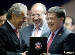 Estrela CEO Carlos Tilkian, left, presents Paraguay's President Horacio Cartes with a gift during a visit to Brazilian toy-maker's factory, Feb, 7, 2017.
