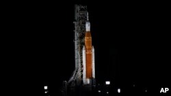 Roket Bulan baru NASA diterangi cahaya lampu terparkir di hanggar Launch Pad 39-B di Kennedy Space Center, Cape Canaveral, Florida, Sabtu, 3 September 2022. beberapa jam sebelum rencana peluncuran, yang kemudian batal karena kebocoran bahan bakar. (Foto: Chris O'Meara/AP)