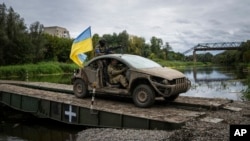 Ukrainian paratroopers with the Ukrainian flag drive on the pontoon bridge across Siverskiy-Donets river in the recently retaken area of Izium, Ukraine, Sept. 14, 2022. 
