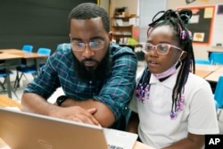 FILE - Ryan Johnson, a fifth-grade teacher at Pecan Park Elementary School, left, checks to see what homework his daughter, Rylei, is bringing home, as they prepare to leave Johnson's classroom in Jackson, Miss., Tuesday, Sept. 6, 2022. (AP Photo/Rogelio V. Solis)