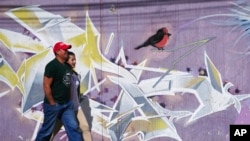 A couple walk past a mural in Quito, Ecuador, April 29, 2022. 