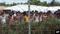FILE - Displaced Rohingya are seen in a fenced-in camp during a government-organized media tour to a no-man's land between Myanmar and Bangladesh, near Taungpyolatyar village, Maung Daw, northern Rakhine State, Myanmar, June 29, 2018.