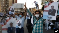 Supporters of Abdolnasser Hemmati, a presidential candidate in the June 18, elections, hold signs with his picture, during a street rally in Tehran, Iran, June 15, 2021.
