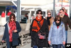 People not wearing face masks walk in Saint-Jean-de-Luz southwestern France, Wednesday, Fev.2, 2022. England, France, Ireland, the Netherlands and several Nordic countries have taken steps to end or loosen their restrictions. (AP Photo/Bob Edme)