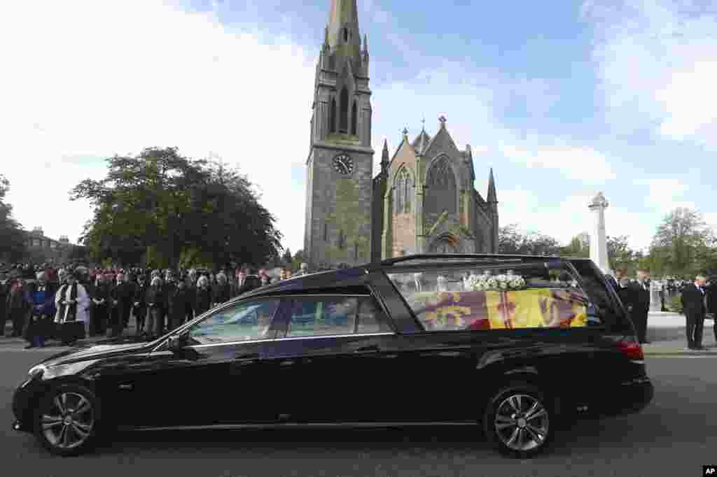 Members of the public line the streets in Ballater, Scotland, as the hearse carrying the coffin of Queen Elizabeth II passes through as it makes its journey to Edinburgh from Balmoral in Scotland, Sept. 11, 2022.