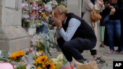 Seorang pelayat terlihat menangis saat memberikan penghormatan di gerbang Istana Buckingham di London, Jumat, 9 September 2022. (Foto: AP)