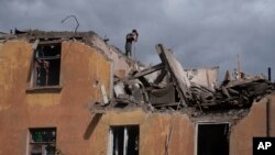 A firefighter works to extinguish a fire as he looks for potential victims after a Russian attack that damaged a residential building in Sloviansk, Ukraine, Sept. 7, 2022.