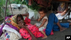 A woman and child rest next to their home damaged by monsoon rains in Hyderabad, Pakistan, Sept. 12, 2022. 