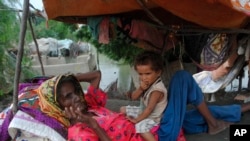 A woman and child rest next to their home damaged by monsoon rains in Hyderabad, Pakistan, Sept. 12, 2022. 