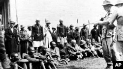 Čuvani od strane pripadnika Lancashire Fusiliersa, policije i odanih Kikuyu kopljanika, osumnjičeni pripadnici Mau Maua ispituju se o ubistvu dvoje Evropljana u blizini Gilgila, Kenija, 8. januara 1953.