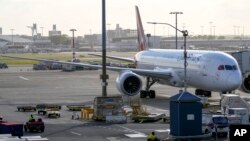 FILE - Ground crew drive their vehicles on the tarmac in the early morning at Sydney Airport, Nov. 29, 2021. Australia will open its borders to all vaccinated tourists and business travelers from Feb. 21.