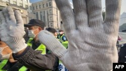 FILE - A policeman blocks the camera to stop journalists from recording footage outside the Shanghai Pudong New District People's Court, in Shanghai, Dec. 28, 2020.